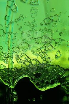 Cool beer foam on green bottle taken closeup suitable as abstract background.
