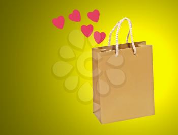 Empty golden valentines gift bag on a yellow background.