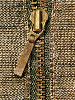 Brass zipper and cotton cloth taken closeup as background.
