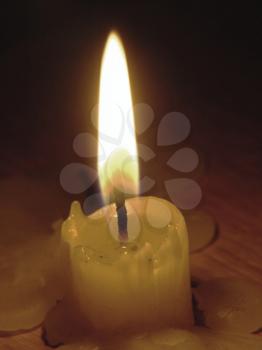 Glowing mourning candle on wooden table in a darkness.
