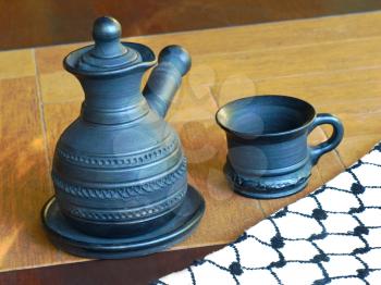 Ceramic coffeepot and cup on a table.