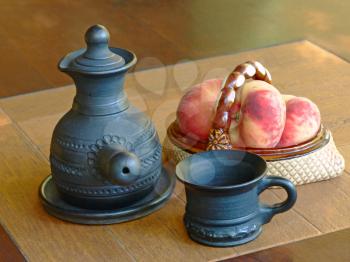 Arabian style coffee pot and ceramic vase with peaches on a table.
