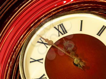 Vintage clock face taken closeup on golden and red twirl abstract background.