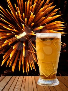Beer glass on wooden table on golden fireworks background.