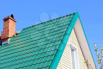 Mint color tiled roof and brick chimney taken closeup.