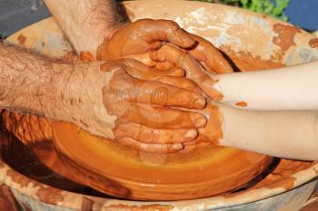 Potter hands wheel pottery work workshop teacher and little pupil. Closeup.