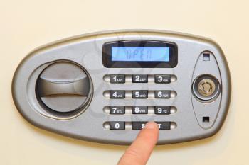 Man finger press start button on electronic home safe taken closeup.