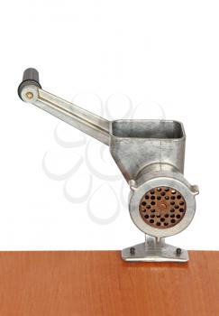 Old manual meat grinder on wooden table and white background.