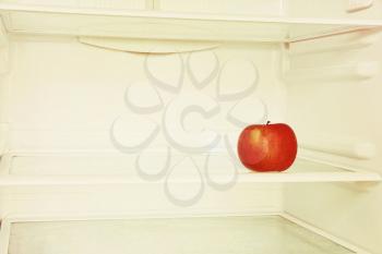 Single red apple in domestic refrigerator taken closeup. Toned image.