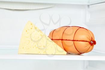 Appetizing cheese and sausage on refrigerator shelf taken closeup.