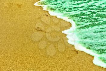 Human traces on sandy beach near turquoise sea surf.Toned image.