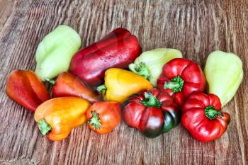 Different kinds of sweet peppers on grunge wooden background taken closeup.Toned image.