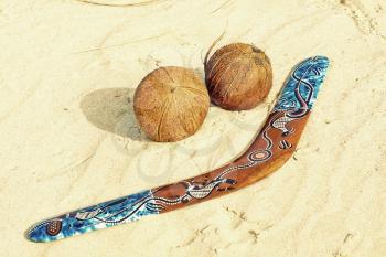 Color boomerang and two coconuts on sandy beach taken closeup.Toned image.