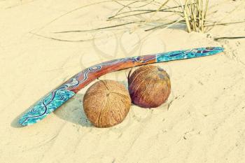 Color Boomerang and two coconuts on sand taken closeup.Toned image.