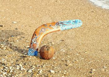 Boomerang and coconut on sandy beach near sea surf.Toned image.