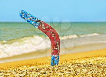 Color Boomerang on Sandy Beach Against of Azure Sea Surf.