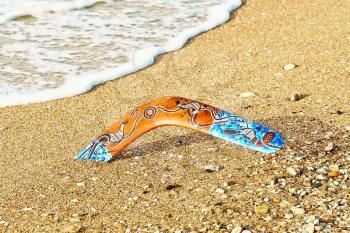Color Boomerang on Sandy Beach near Sea Surf.