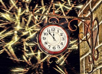 Clock face and brick wall on golden firework stars background.New Year eve.