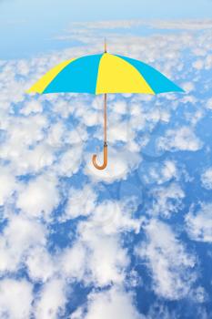 Umbrella in Ukrainian flag colors flies in sky against of white clouds.Mary Poppins Umbrella.Wind of change concept.