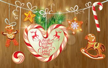 Holiday greeting Card with xmas gingerbread, candy and fir-tree branches. Hand written calligraphic text Merry Christmas and Happy New Year on wooden background. 