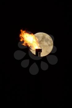 Full moon behind natural gas flame