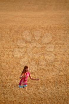 Redhead girl walking in a Saskatchewan wheat field