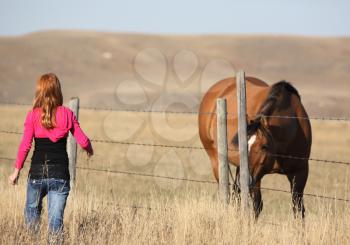 Young girl approaching horse in scenic Saskatchewan