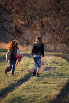 Two girls running along causeway in scenic Saskatchewan