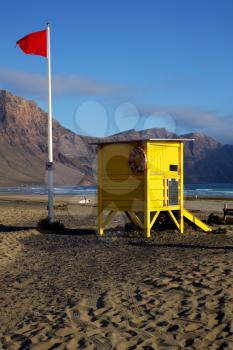 red flag water lifeguard chair cabin in spain  lanzarote  rock stone sky cloud beach  musk pond  coastline and summer 
