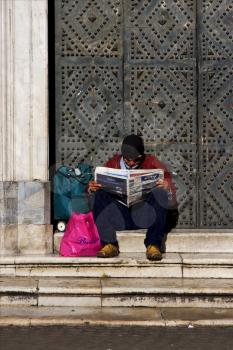 the brown gate  in the church gesu nuovo in naples and a hompless reading a newspaper
