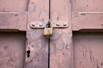 abstract  padlock rusty brass brown knocker in a   closed wood door crenna gallarate varese italy