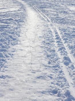 Snow covered park trail with parallel thereto ski track in a sunny winter day