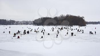 Winter scene. Fishermans on the surface of frozen reservoir 
