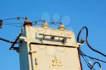 Old transformer with insulators and wires on a background azure sky