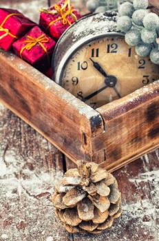 outdated watch in wooden box on the background of Christmas decorations and pine cones.