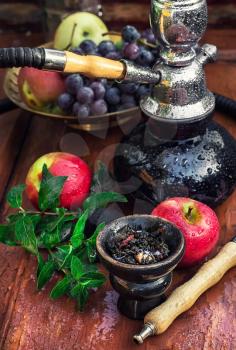 Hookah with fruit flavour on wooden table in vintage style