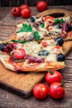 meat pizza made with salami,cheese,mushrooms,cherry tomatoes and olives.The image is tinted.