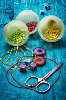 coil,beads and tools for needlework on turquoise wooden background