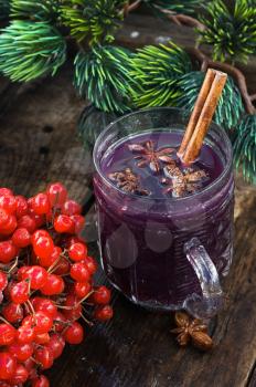 A glass of wine with the cinnamon stick and star anise amid the branches of the spruce.