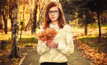 Beautiful girl in autumn Park with maple listeme in the hands