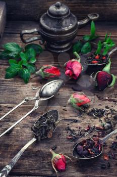 Stylish spoons with variety of tea on vintage wooden board.
