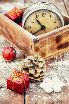 Stylish wooden box with clock on the background of pine cones and Christmas decorations