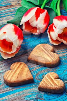 light bouquet of red tulips and  wooden heart symbolic