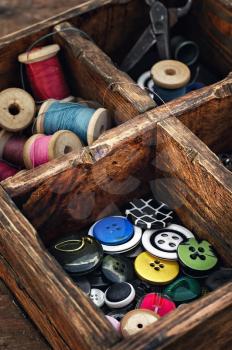 Sewing kit with threads and buttons in the cells wooden box