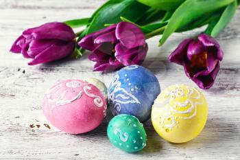 Decorated with painted Easter eggs and flowers on light background