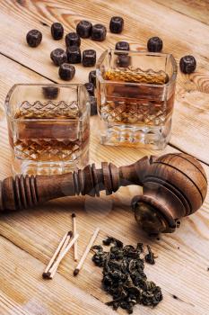 Smoking pipe in a retro style,dark chocolate and glasses of whiskey on wooden background