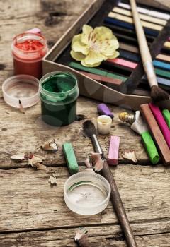 Crayons and paints for painting on wooden background