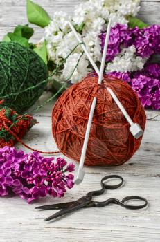  clew of wool yarn for knitting and branches of lilac blossoms