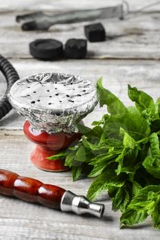 Eastern hookah with mint flavor of tobacco on a light wooden background