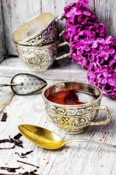 Stylish and fashionable cup of tea and branch of blossoming lilac